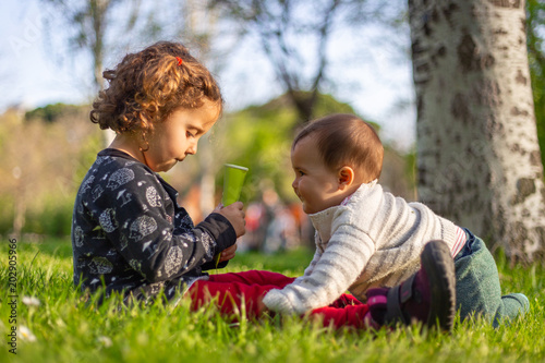 Two sisters playing in the grass in a park