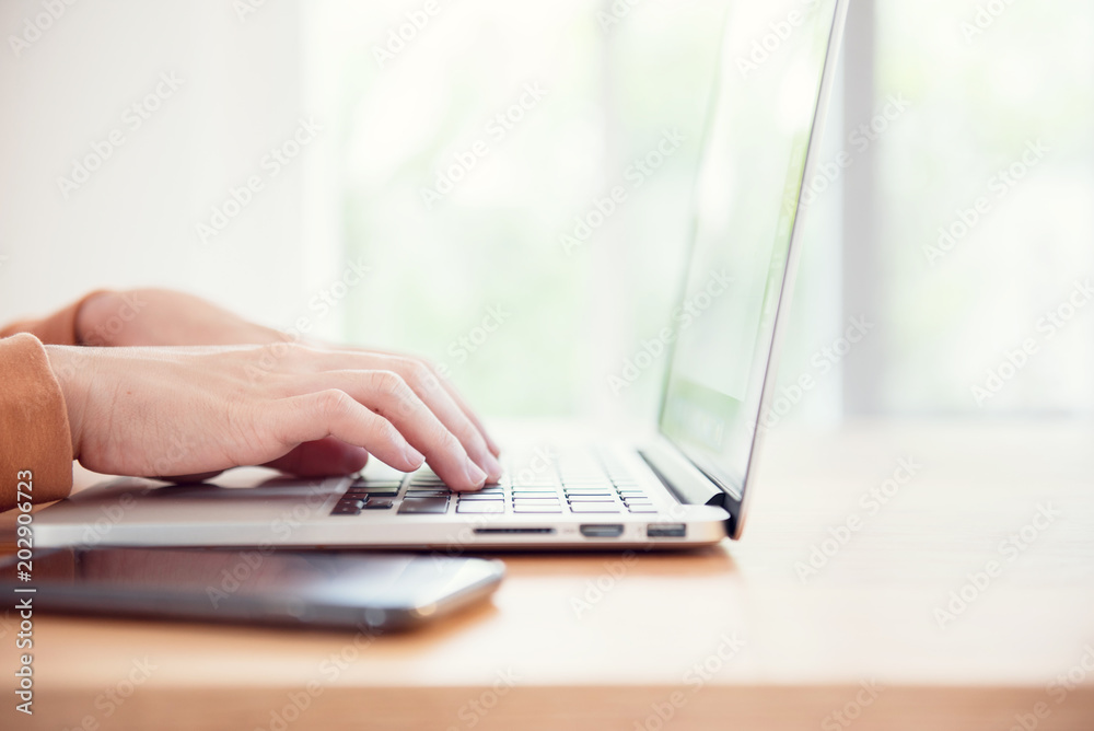 Closeup woman's hands typing on a laptop on a wooden desk. Closeup woman's hands typing on a laptop on a wooden desk.