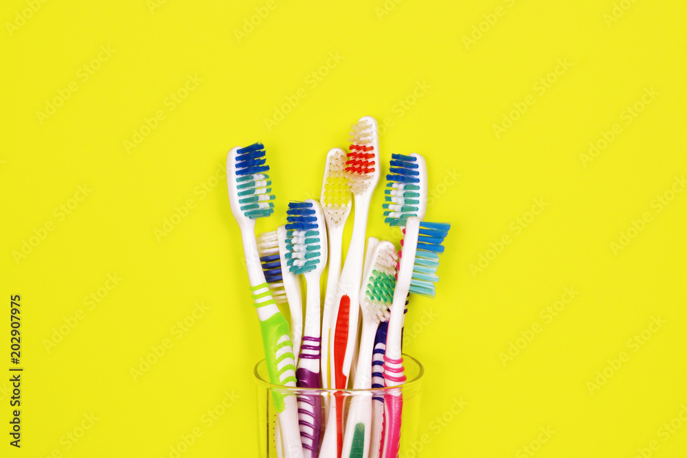 Toothbrushes in a glass on yellow background Toothbrushes in a glass on yellow background