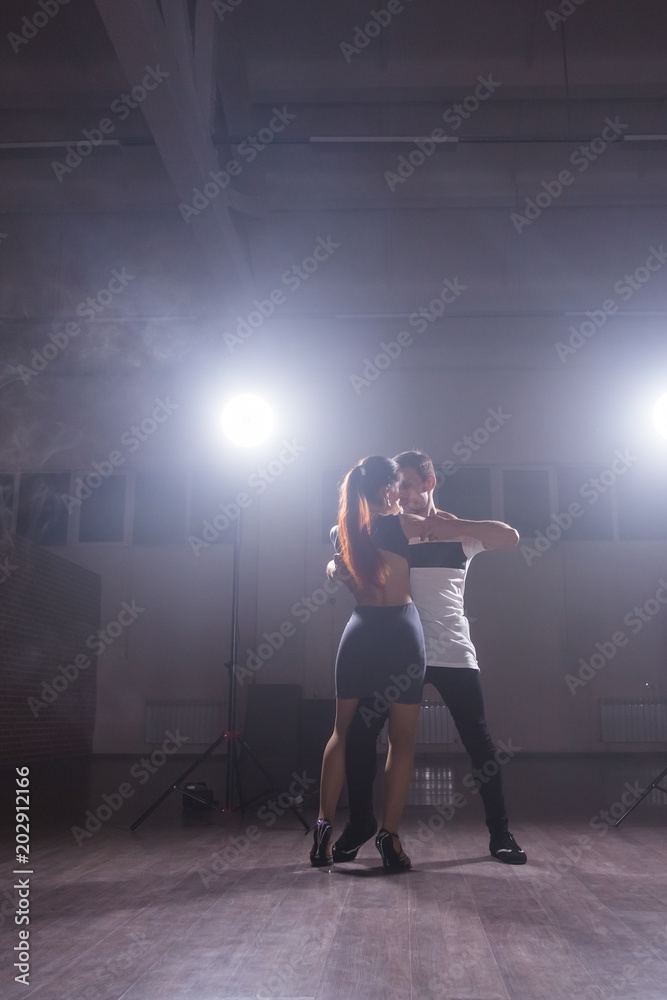 Skillful dancers performing in the dark room under the concert light and smoke. Sensual couple performing an artistic and emotional contemporary dance Skillful dancers performing in the dark room under the concert light and smoke. Sensual couple performing an artistic and emotional contemporary dance