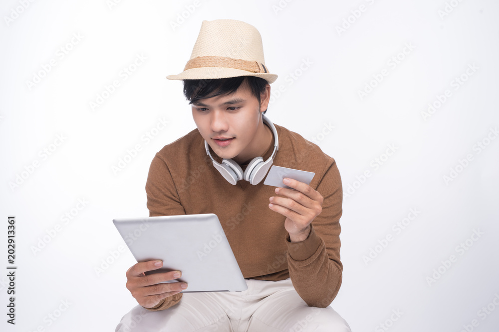 Smart casual asian man seated on chair, shopping online with credit card and smartphone Smart casual asian man seated on chair, shopping online with credit card and smartphone