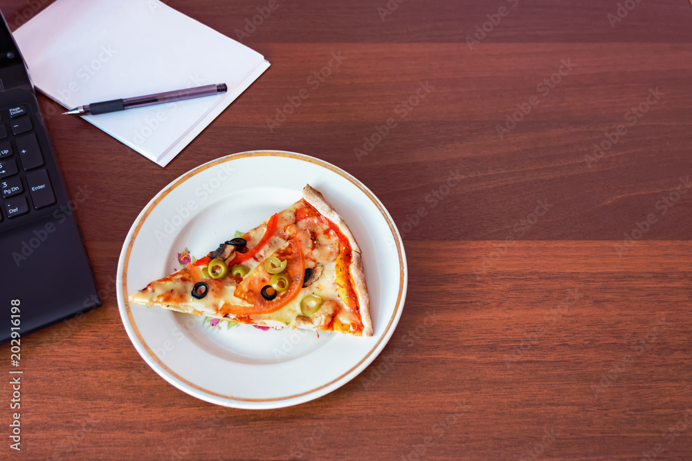 A piece of pizza on the desktop. Lunch break in the office. Flat lay A piece of pizza on the desktop. Lunch break in the office. Flat lay