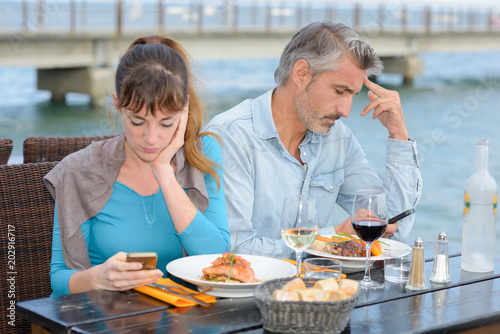Obraz na plátne Couple having meal both preoccupied with cellphones
