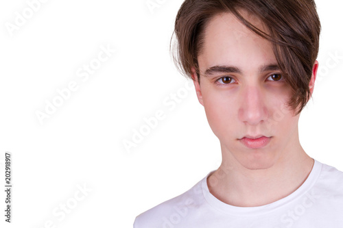 Handsome teen boy looking at camera. Closeup portrait of teenager in white T-shirt, isolated on white background