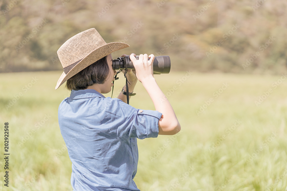 Woman wear hat and hold binocular in grass field Woman wear hat and hold binocular in grass field