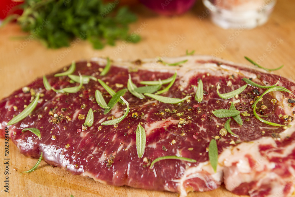 Ripened seasoned beef rump or striploin steak on wooden cut board prepared for cooking Ripened seasoned beef rump or striploin steak on wooden cut board prepared for cooking