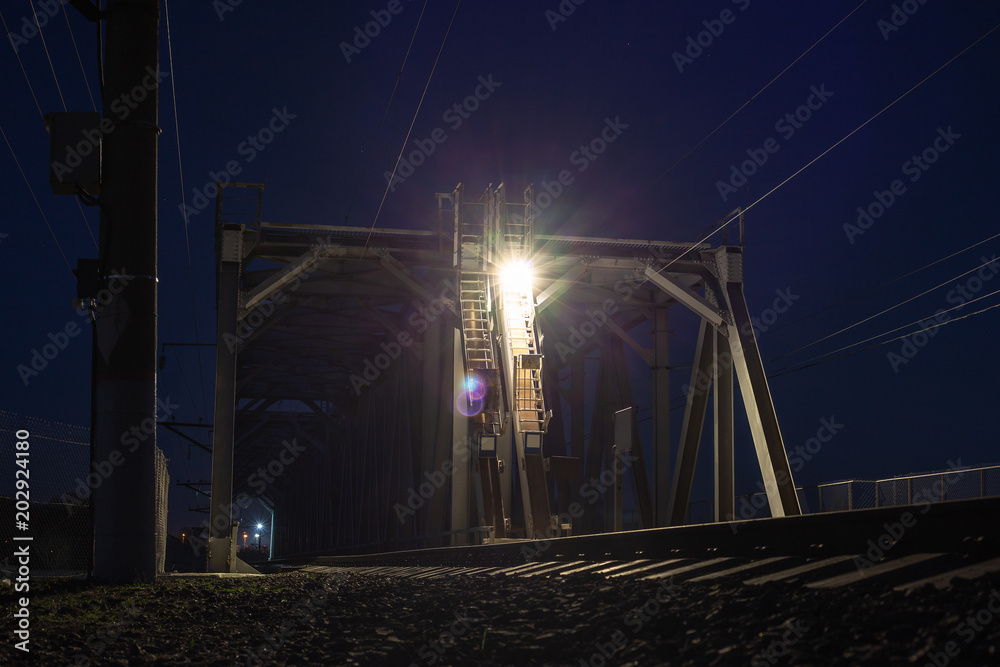 Railroad bridge over river at night, transportation construction