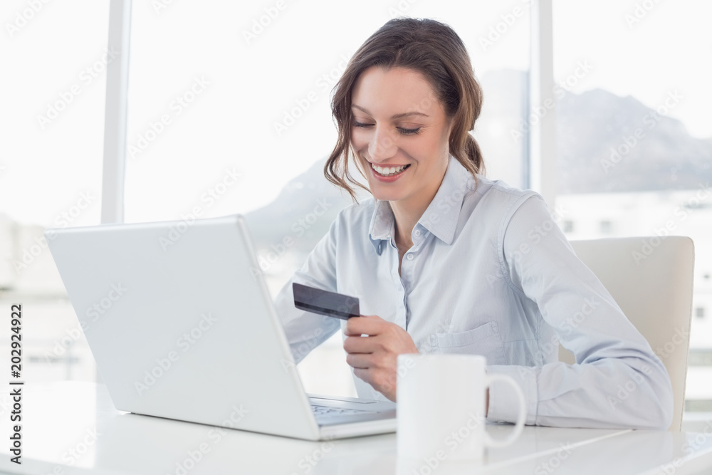 Smiling businesswoman doing online shopping in office Smiling businesswoman doing online shopping in office