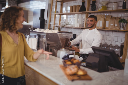 Smiling waiter looking at female customer standing at counter