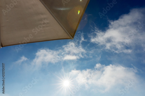 Part of beach umbrella with blue sky and cloud in hard sun light
