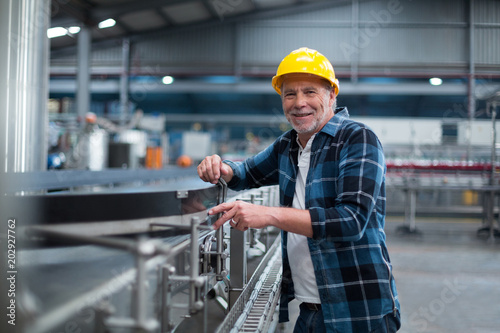 Portrait of smiling factory worker near production line