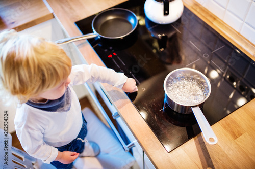 Toddler boy in dangerous situation at home. Child safety concept.