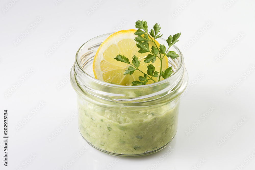 Mexican sauce guacamole in a jar with lemon slice and parsley isolated on white. Mexican sauce guacamole in a jar with lemon slice and parsley isolated on white.
