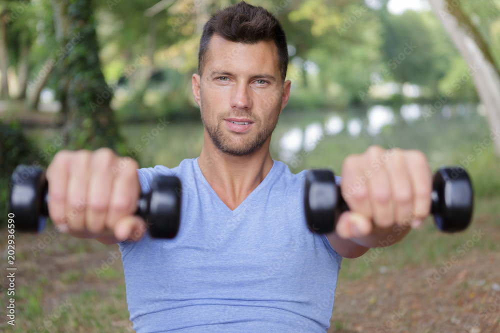 sports man doing workout with small dumbbells outdoors sports man doing workout with small dumbbells outdoors