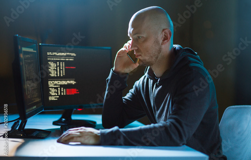 Fotografija cybercrime, hacking and technology concept - male hacker in dark room using comp