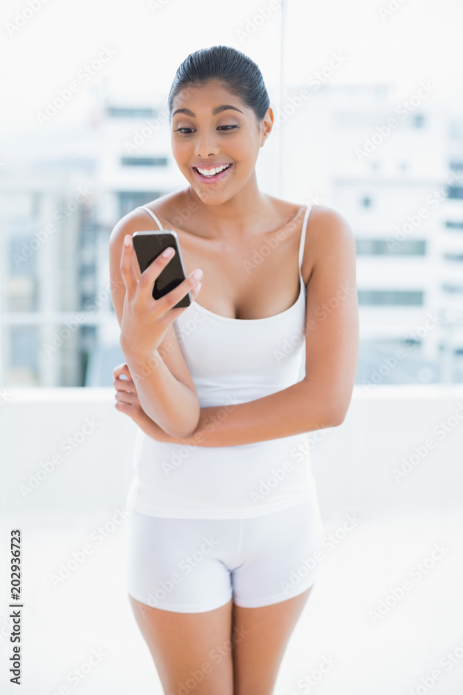 Surprised toned brunette holding smartphone