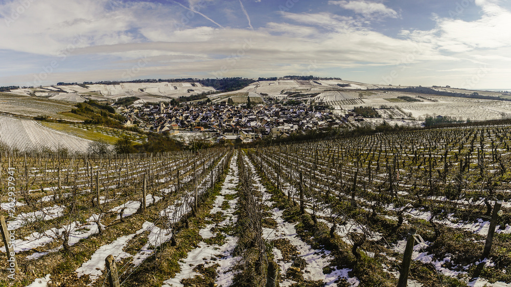 Fototapeta Na dnie doliny ośnieżona wioska, wzgórza i winnice