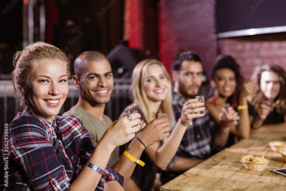 Cheerful friends sitting side by side at table Cheerful friends sitting side by side at table