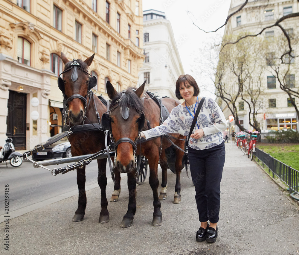 Φωτογραφία Vienna, Austria. Girl tourist stroking horses in a carriage.