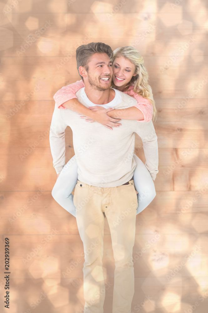 Handsome man giving piggy back to his girlfriend against light glowing dots design pattern Handsome man giving piggy back to his girlfriend against light glowing dots design pattern
