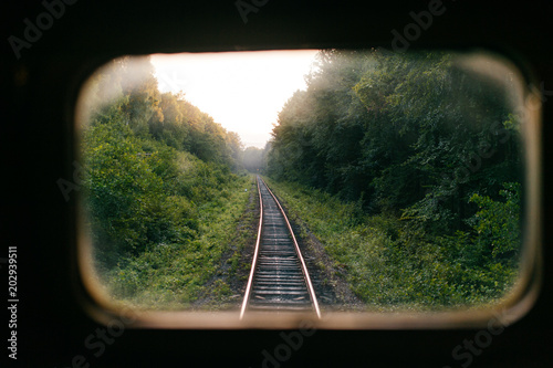 Train travel. Beautiful far scenic view through window from riding train at railway with nature ladnscape at sunset. Tourist trip. Atmospheric lifestyle journey.  End of weekend.  Farewell vacation.