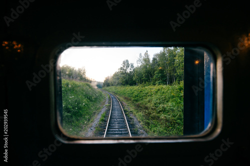 Train travel. Beautiful far scenic view through window from riding train at railway with nature ladnscape at sunset. Tourist trip. Atmospheric lifestyle journey. End of weekend. Farewell vacation.