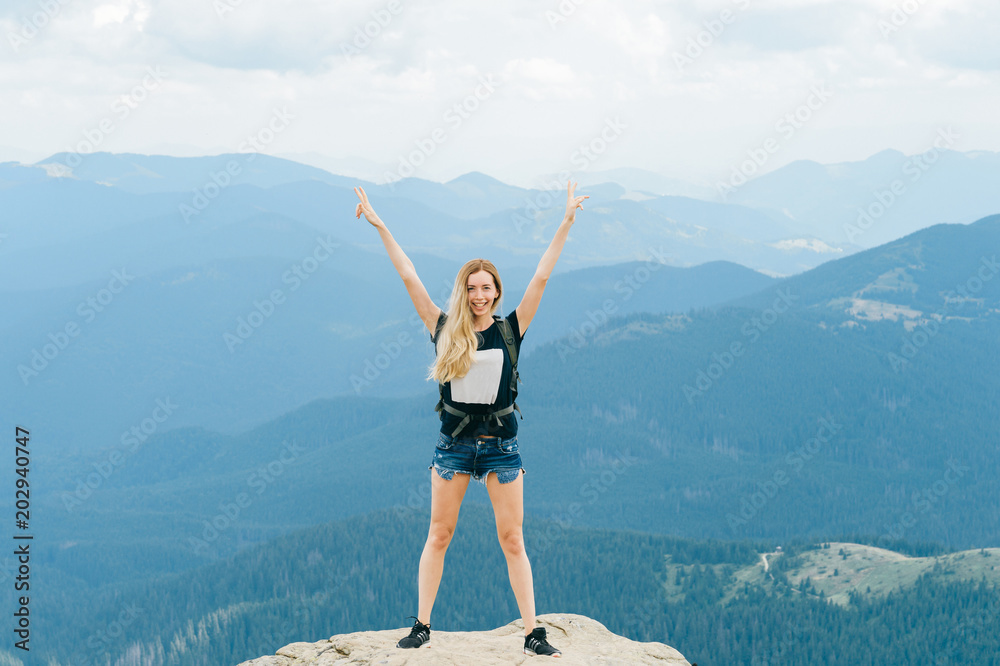 Happy beautiful young sexy babe enjoying success after reaching top of mountain. Healthy active lifestyle. Blonde traveler girl hiker standing on stone at hill edge with beautiful far view beyond. Happy beautiful young sexy babe enjoying success after reaching top of mountain. Healthy active lifestyle. Blonde traveler girl hiker standing on stone at hill edge with beautiful far view beyond.
