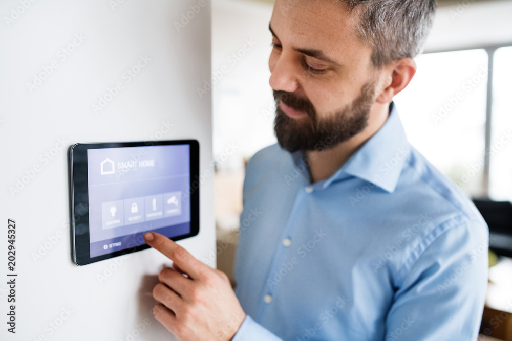 A man pointing to a tablet with smart home screen at home. A man pointing to a tablet with smart home screen at home.