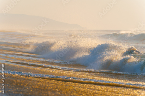 Mediterranean cost ar sunset. Tropical island shore with strong stormy waves in motion. Sunlight on yellow sand beyond ocean. Paradise picturesque seascape. Beautiful nature seaside landscape. Relax.