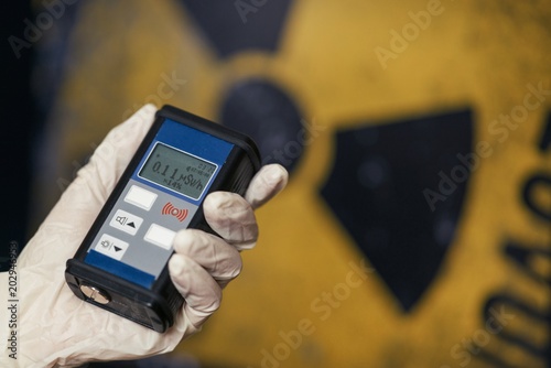 Radiation supervisor in glove with geiger counter checks the level of radiation photo