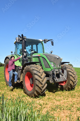 portrait of a farmer woman and tractor on the field