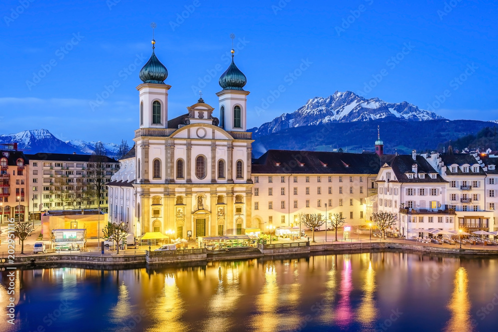 The lights of the Jesuit Church (Jesuitenkirche in German) reflecting in the Reuss river at night in Lucerne, Switzerland