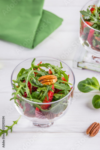 Salad with strawberries, pecan nuts and arugula on a white background