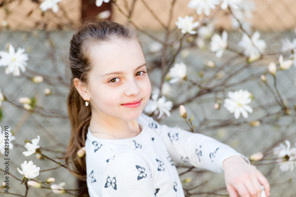Beauty girl on floral blossom in spring. Beauty kid with fresh look and long hair