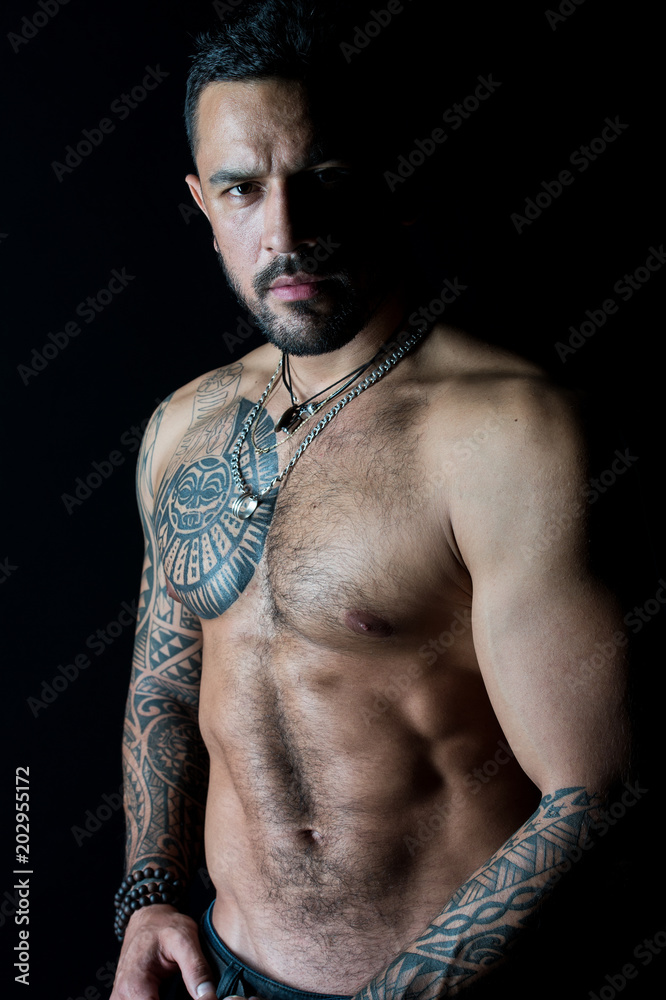 Fit model with tattoo art on skin. Bearded man with tattooed chest. Macho  with sexy bare