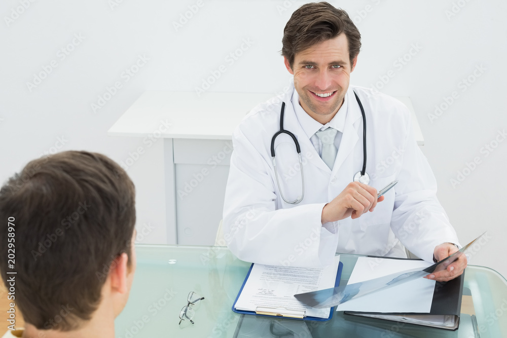 Smiling doctor explaining xray reports to patient Smiling doctor explaining xray reports to patient
