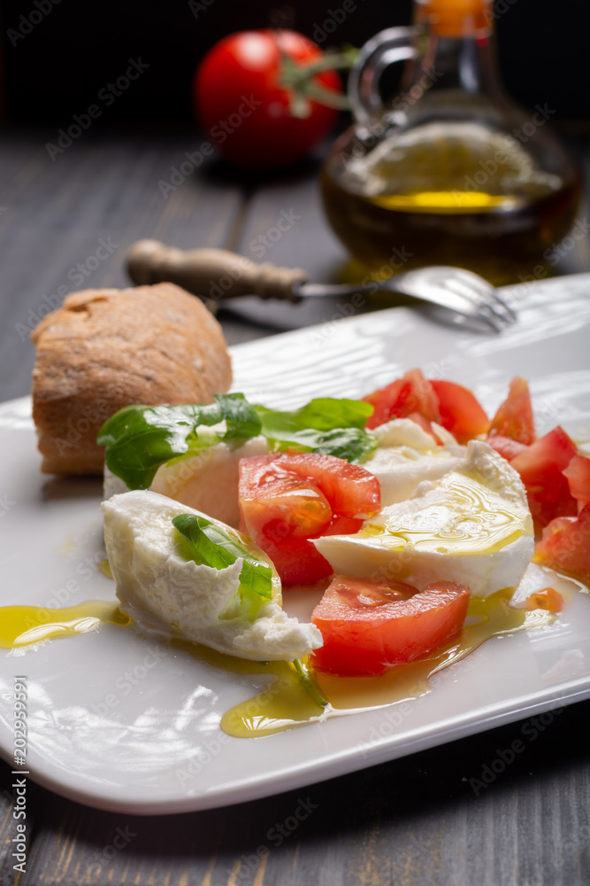 Caprese salad with tomatoes, basil, mozzarella balls, made with white ball mozzarella buffalo Italian soft cheese and olive oil Caprese salad with tomatoes, basil, mozzarella balls, made with white ball mozzarella buffalo Italian soft cheese and olive oil