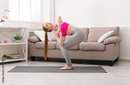 Woman training yoga in twisting awkward pose.