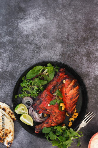 Tandoori chicken half, with bone, lime and raita. Top view, blank space