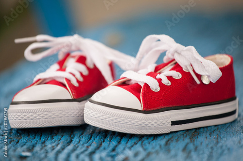Red baby sneakers on wooden blue background