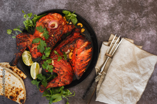 Indian tandoori chicken with naan, lime slices and cilantro, ready to eat. Top view, blank space photo