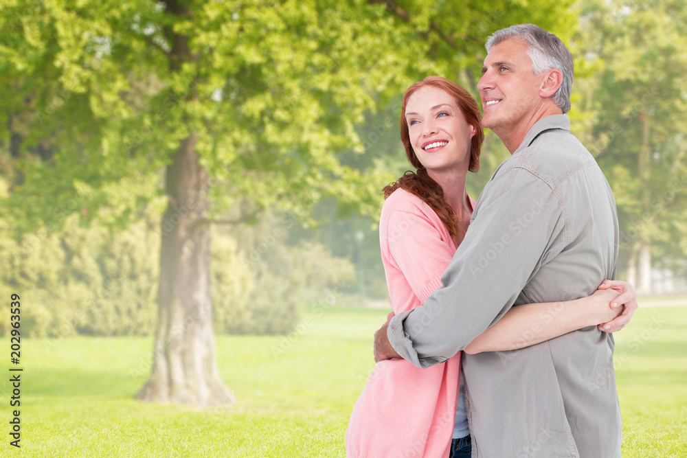 Casual couple hugging and smiling against trees and meadow Casual couple hugging and smiling against trees and meadow