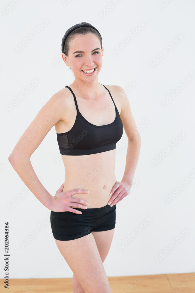 Smiling toned woman with hands on hips in fitness studio Smiling toned woman with hands on hips in fitness studio