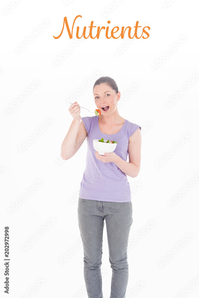 The word nutrients against gorgeous woman eating a bowl of salad while standing The word nutrients against gorgeous woman eating a bowl of salad while standing