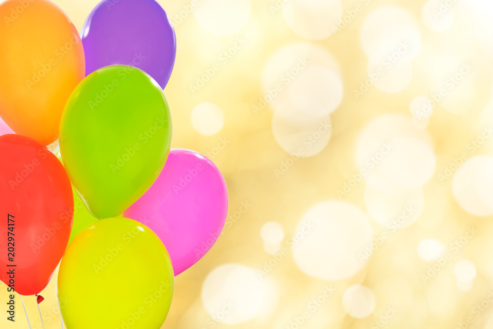 Party decoration concept - mix of colorful balloons on a bright yellow background with bokeh effect (copy space).