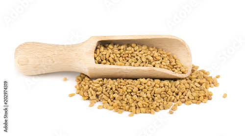 Fenugreek seeds in wooden spoon, isolated on white background