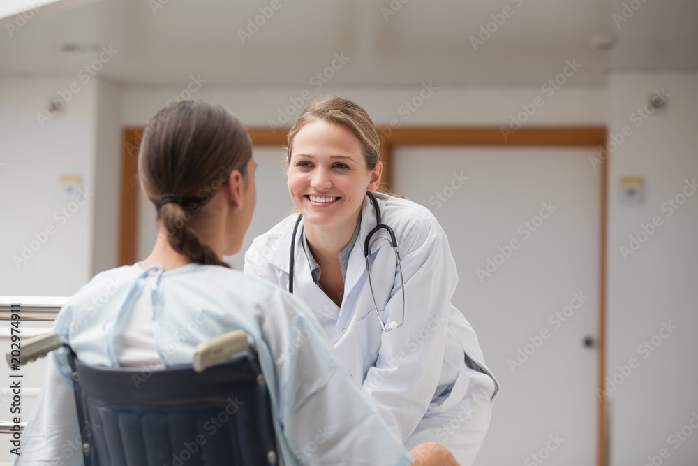 Smiling doctor in front of a patient on a wheelchair Smiling doctor in front of a patient on a wheelchair
