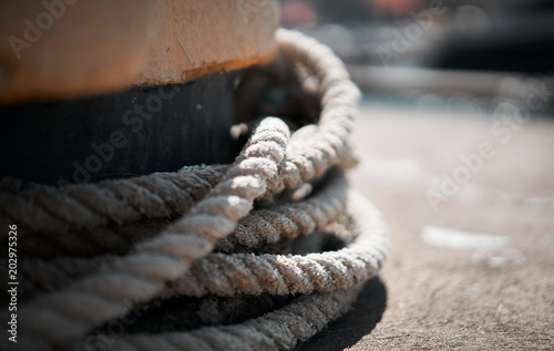 Bollard at the pier. Bollard with rope. Beautiful blurred pier in the background