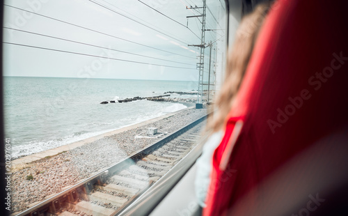 Closeup of a train seat. Beautiful view from the train window to the sea. Travel by train by sea. The girl sits at the window and looks at the blue sea. Railways from the window