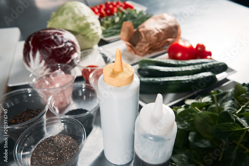 Closeup of sauces for cooking. The chef prepares food in the professional kitchen. Spices on the table. Cucumbers, tomatoes, onions, cabbage and greens for cooking salad. Master class from the chef. W